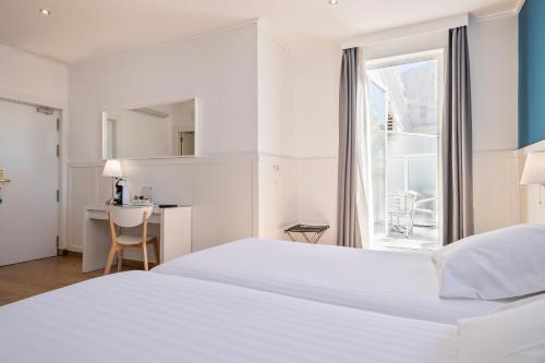 a white bedroom with a bed and a desk and a window at Venecia Plaza Centro in Valencia