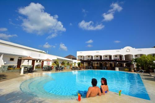 Dos personas sentadas en la piscina de un complejo en Panglao Regents Park Resort, en Panglao