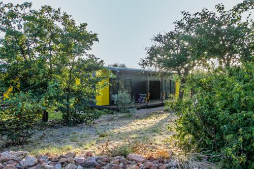a yellow and gray house in a field with trees at SleepOver Orpen Gate in Acornhoek