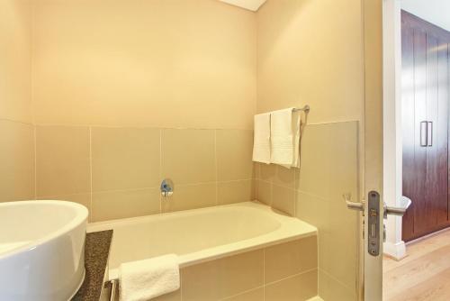 een badkamer met een bad en een wastafel bij A Modern unit, self checkin, restaurants and shops below in Kaapstad