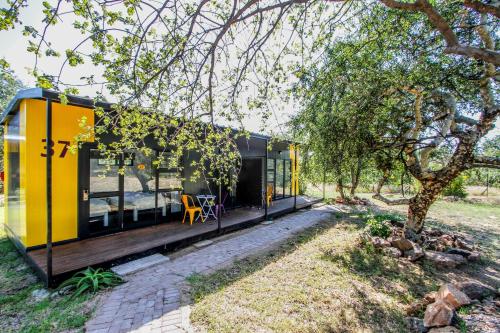 a yellow and black house with a wooden deck at SleepOver Orpen Gate in Acornhoek