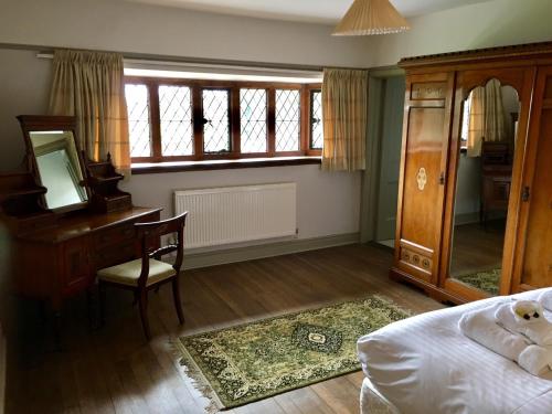 a bedroom with a bed and a desk and a mirror at Thornton Manor - Holiday Cottages and Apartments in Heswall