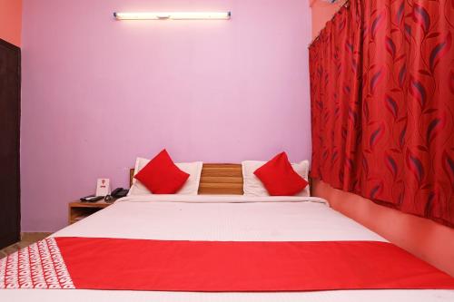a bedroom with a large bed with red pillows at OYO Silver Inn Near Acropolis Mall in Jādabpur