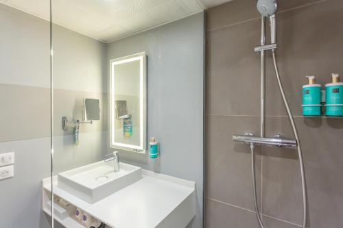 La salle de bains est pourvue d'un lavabo et d'une douche. dans l'établissement Novotel Bourges, à Bourges