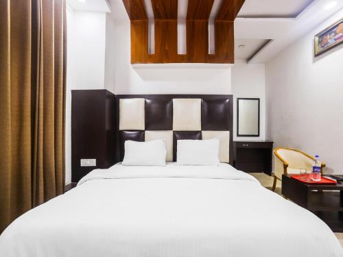 1 dormitorio con 1 cama blanca grande y cabecero negro en OYO Hotel Br Villa, en Nārnaul