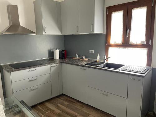 d'une cuisine avec des placards blancs, un évier et une fenêtre. dans l'établissement Al vecchio Mulino, à Lastra a Signa