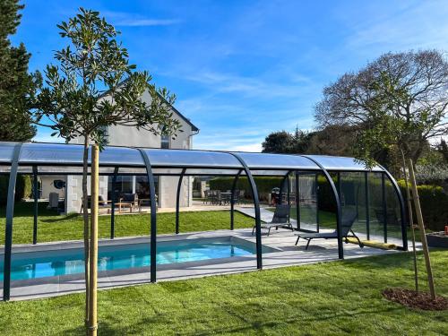 une maison en verre avec une piscine et un arbre dans l'établissement Belle maison avec piscine proche plages Saint-Cast, à Saint-Cast-le-Guildo