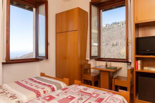 1 dormitorio con 1 cama, escritorio y 2 ventanas en Albergo Sacro Monte Varese, en Varese