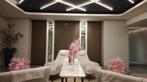 - un hall avec des chaises blanches et une table ornée de fleurs roses dans l'établissement Iproperti, à Jakarta