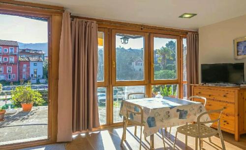 une pièce avec une table et des chaises et une grande fenêtre dans l'établissement Apartamentos Camparina, à Llanes