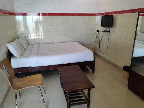 Habitación pequeña con cama, mesa y silla en Flagship Mak Residence, en Shamshabad