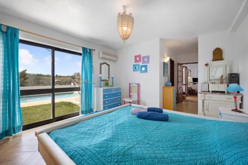 a bedroom with a blue bed with a large window at Vila Portimão T5 com Piscina in Portimão