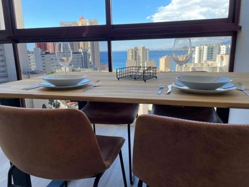 drewniany stół z krzesłami i talerzami oraz kieliszki do wina w obiekcie GEMELOS 15 TURIS - PREMIUM Apartamentos w mieście Benidorm