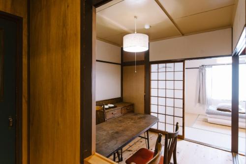 a room with a wooden table and a bedroom at Guesthouse RICO in Wakayama