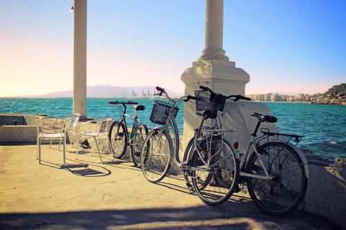 três bicicletas estacionadas contra uma parede ao lado da água em Hostal Moscatel em Málaga