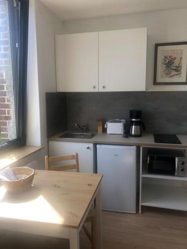 - une cuisine avec des placards blancs et une table avec un bol dans l'établissement CHEZ ROMY, MAISON AVEC PARKING ET JARDIN, au Tilleul