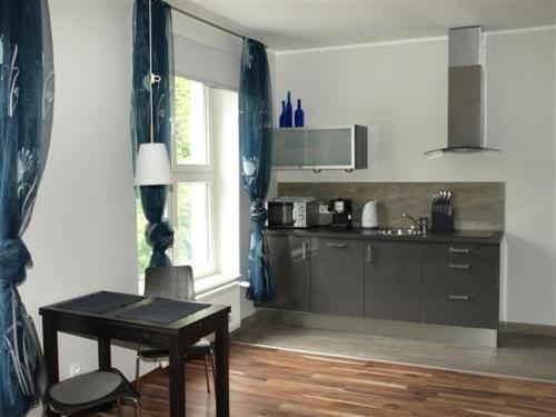 グダニスクにあるGrand Tourist Apartment Merlinの窓、テーブルとテーブル付きのキッチンが備わります。