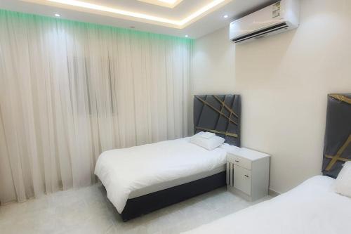 a small bedroom with two beds and a television at راحتك - إقامة وفخامة in Mecca