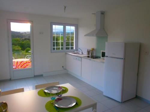 une cuisine avec un réfrigérateur blanc et une table dans l'établissement les lauriers, à Vinezac