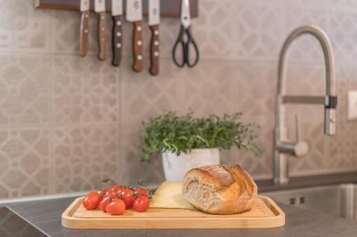 a cutting board with a loaf of bread and tomatoes on a kitchen counter at Landhaus Wiederkehr in Oberstdorf