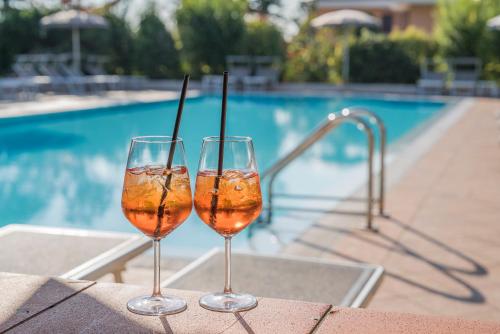 two glasses of wine sitting on a table near a swimming pool at Hotel Gardenia in Sirmione