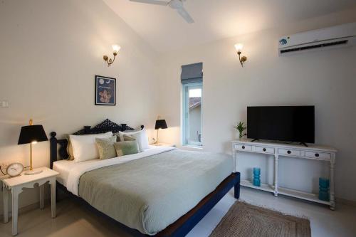 a bedroom with a large bed and a flat screen tv at Mediterranean Bliss by VEO - Part of StayVista in Sangolda