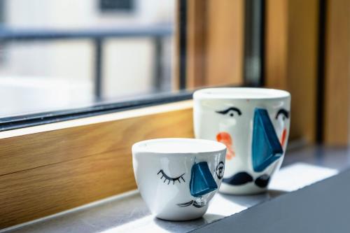 two cups with faces painted on them sitting on a counter at Athens Feeling in Athens