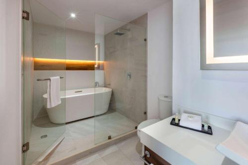 a white bathroom with a tub and a sink at Wyndham Puebla Angelopolis in Puebla