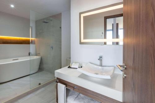 La salle de bains est pourvue d'un lavabo, d'une baignoire et d'un miroir. dans l'établissement Wyndham Puebla Angelopolis, à Puebla