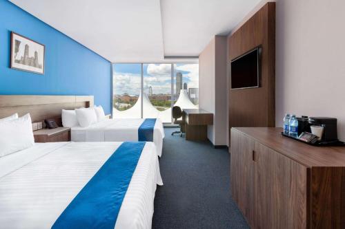 a hotel room with two beds and a television at Wyndham Puebla Angelopolis in Puebla