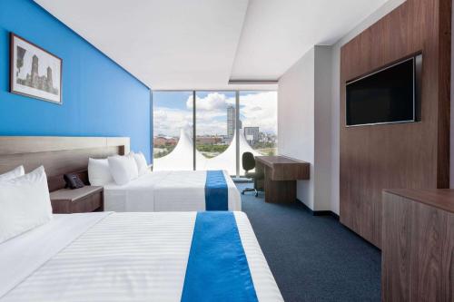 a hotel room with two beds and a flat screen tv at Wyndham Puebla Angelopolis in Puebla