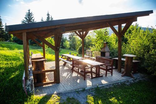a wooden pavilion with a picnic table and benches at Resort Drevenice Terchova in Terchová