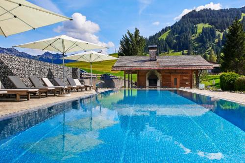 a swimming pool with chairs and a gazebo at Hotel Hohenfels in Tannheim