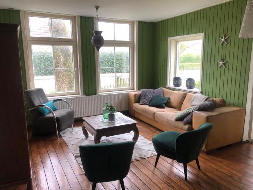 uma sala de estar com paredes verdes e um sofá e cadeiras em De Witte Handt em Midsland