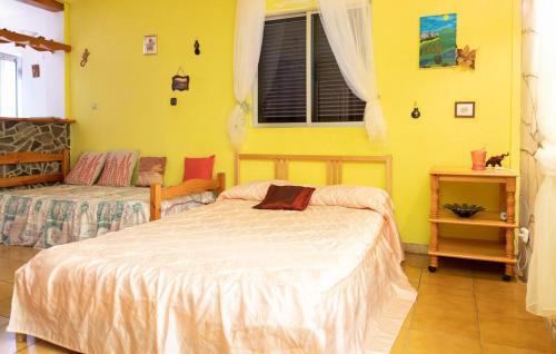 1 dormitorio con 2 camas y pared amarilla en Casa Majores, en Lo del Gato