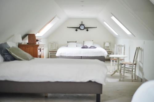 ein Schlafzimmer mit 2 Betten und einer Uhr an der Wand in der Unterkunft Gastenverblijf Huize Pervijze in Pervijze