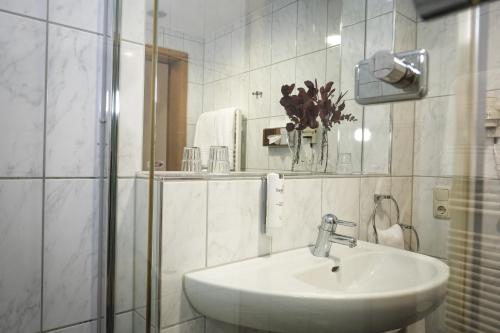 a white bathroom with a sink and a mirror at Hotel-Restaurant Zur Mühle in Schermbeck