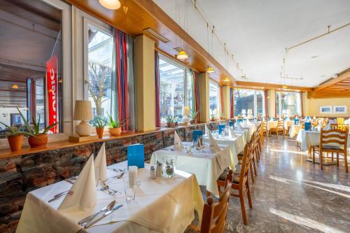 a restaurant with white tables and chairs and windows at Der Schütthof in Zell am See