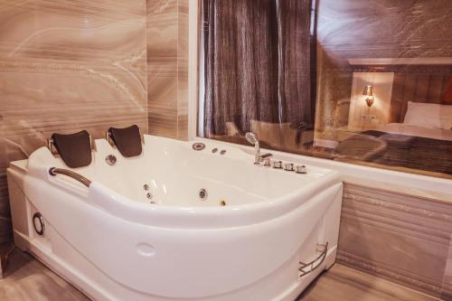 a bath tub in a bathroom with a bed at Nafron Hotel in Prizren