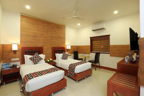 Eloor Tourist Home في إرناكولام: غرفة فندقية بسريرين وتلفزيون بشاشة مسطحة