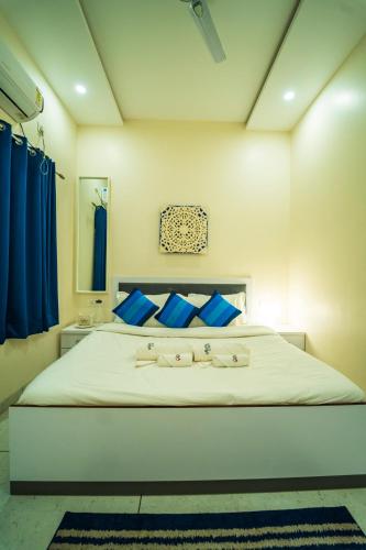 a bedroom with a large white bed with blue pillows at Spicy Mango Villa Gardena - Luxurious Villa In Karjat in Thākurvādi