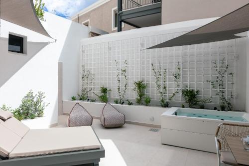 um pátio com uma banheira e plantas numa parede em Porta Suites em Heraclião