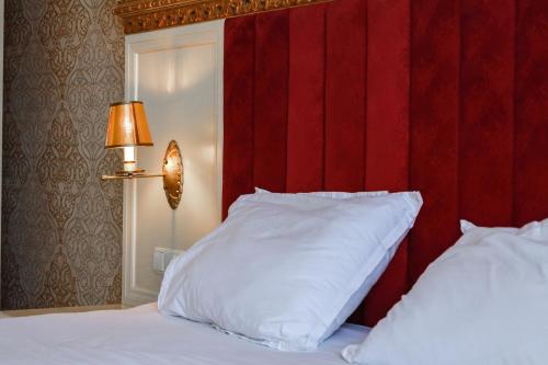 a bed with a red headboard and a white pillow at Nafron Hotel in Prizren