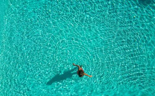 a person swimming in a pool of blue water at Monte das Lages in Redondo