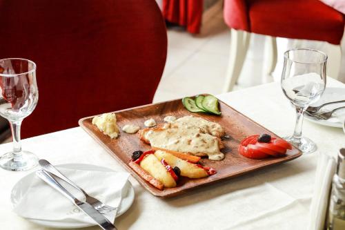 a plate of food on a table with wine glasses at Nafron Hotel in Prizren