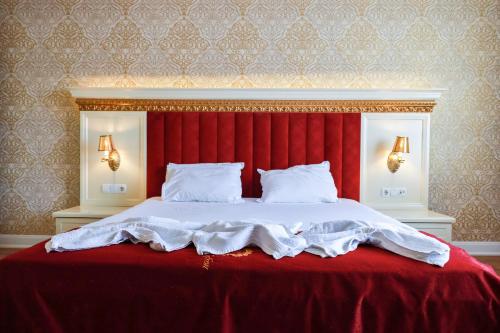 a bed with a red headboard and a red blanket at Nafron Hotel in Prizren