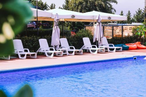 a group of chairs and umbrellas next to a swimming pool at Nafron Hotel in Prizren