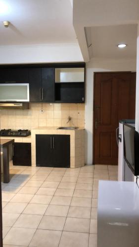 a kitchen with black cabinets and a tile floor at Promo Mediterania Palace Kemayoran in Jakarta