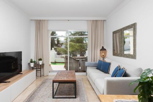 uma sala de estar com um sofá e uma televisão em Bright 2 Bedroom apartment with parking space and swimming pools in Aloha Gardens em Marbella
