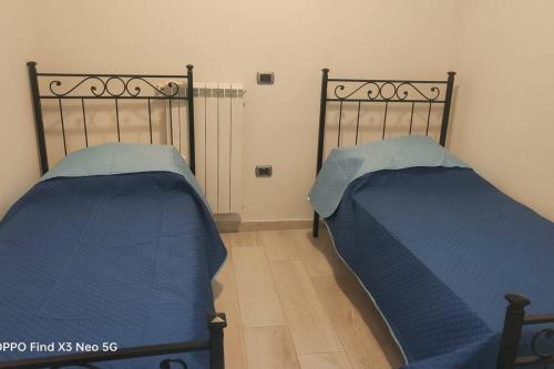 two beds in a room with blue sheets at Pompei Priscus I Casa Vacanza in Scafati